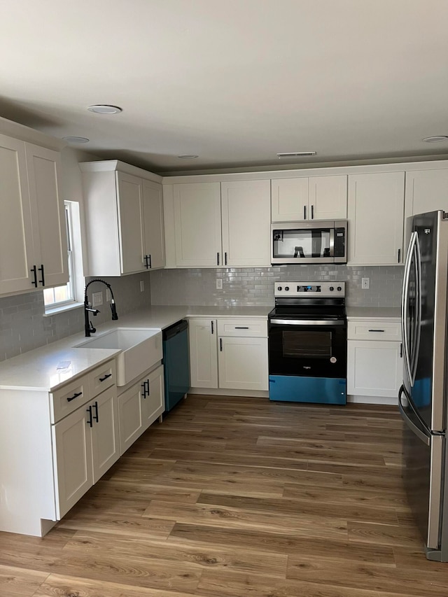 kitchen featuring white cabinets, sink, wood-type flooring, and stainless steel appliances