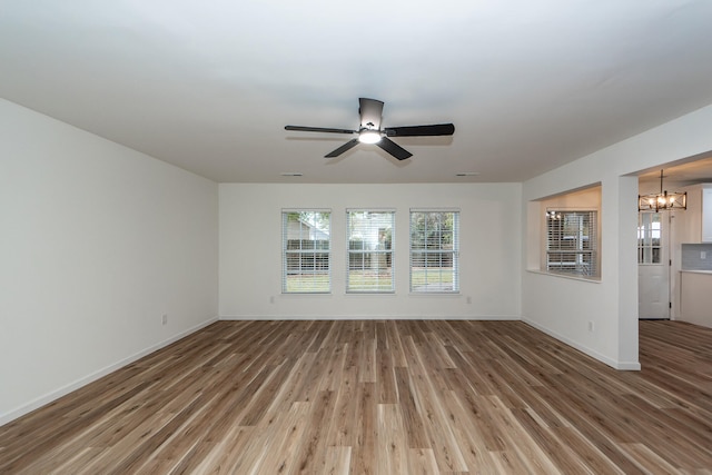 unfurnished living room with hardwood / wood-style floors and ceiling fan with notable chandelier