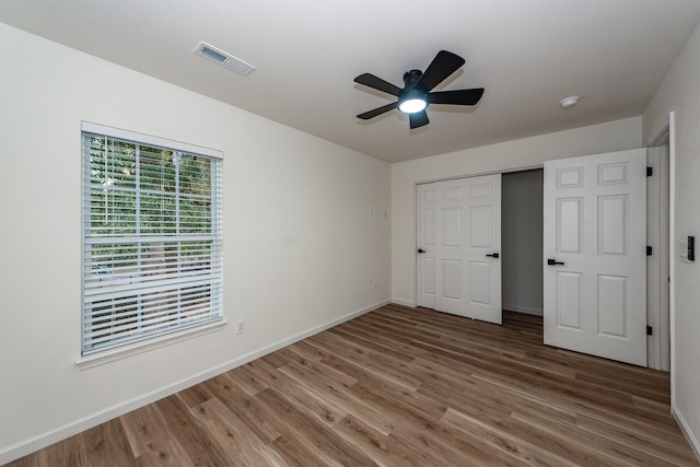 unfurnished bedroom featuring hardwood / wood-style floors, ceiling fan, and a closet