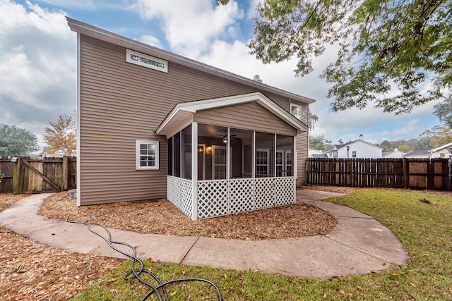 rear view of house featuring a lawn and a sunroom