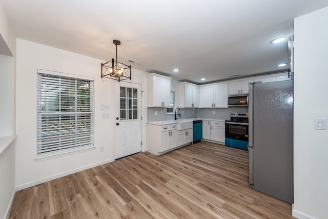 kitchen with pendant lighting, light wood-type flooring, white cabinetry, and stainless steel appliances