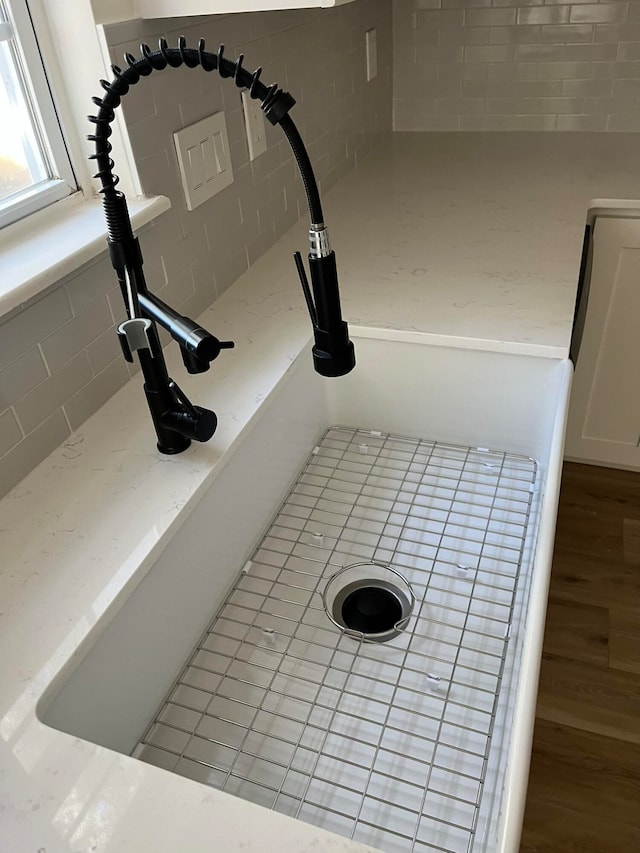 interior details featuring wood-type flooring, white cabinetry, and sink