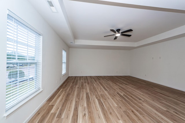 spare room with a raised ceiling, ceiling fan, plenty of natural light, and hardwood / wood-style flooring