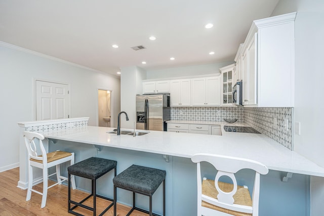 kitchen with light hardwood / wood-style floors, a kitchen bar, stainless steel appliances, sink, and white cabinetry