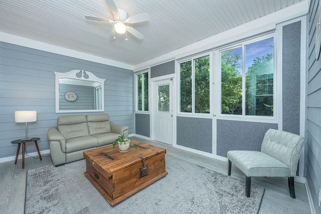 living room featuring wood-type flooring, wood walls, and ceiling fan