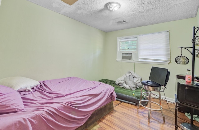 7074 W Constellation Dr, North Charleston, SC 29418 - bedroom featuring wood finished floors, a textured ceiling, and cooling unit