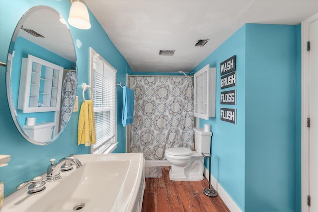 bathroom with hardwood / wood-style floors, a shower with curtain, toilet, and sink