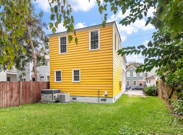 back of property with central AC unit and a lawn