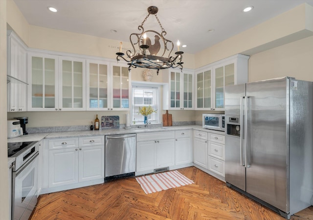 kitchen featuring hanging light fixtures, white cabinets, and stainless steel appliances