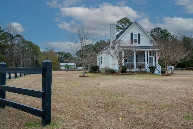 view of side of property with covered porch and a yard