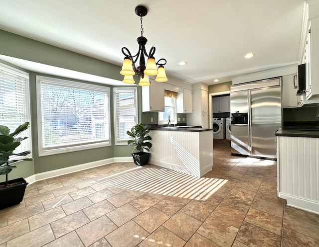 kitchen featuring hanging light fixtures, washing machine and dryer, appliances with stainless steel finishes, and white cabinetry