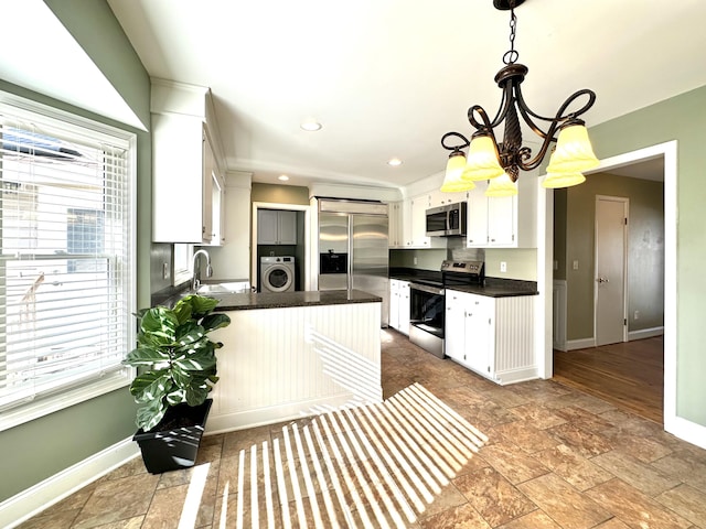 kitchen featuring decorative light fixtures, washer / clothes dryer, sink, white cabinets, and stainless steel appliances