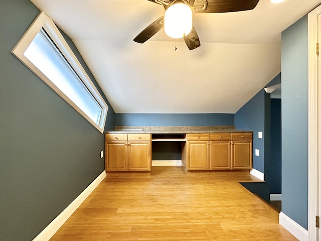 bonus room featuring lofted ceiling, built in desk, ceiling fan, and light wood-type flooring