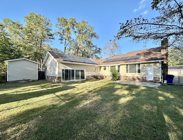 rear view of house with a patio, a yard, and solar panels