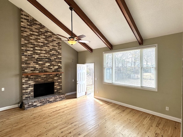 unfurnished living room featuring beamed ceiling, a fireplace, light hardwood / wood-style flooring, and a textured ceiling