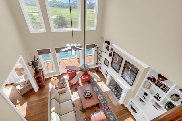 living room with wood-type flooring, a towering ceiling, and ceiling fan