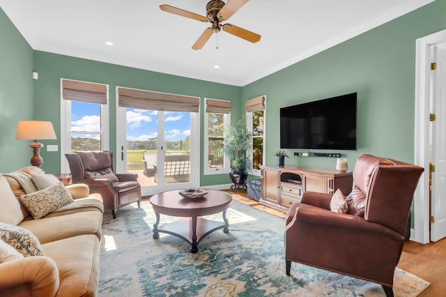 living room featuring crown molding, light hardwood / wood-style flooring, and ceiling fan