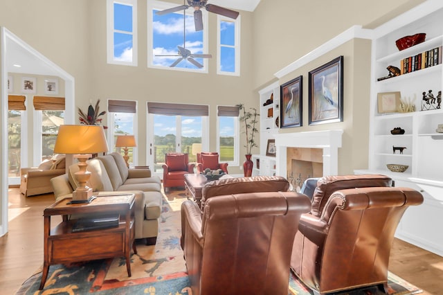 living room featuring a tiled fireplace, ceiling fan, and light hardwood / wood-style floors