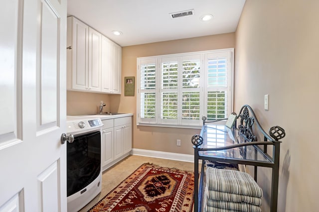 clothes washing area with cabinets, sink, and light tile patterned floors