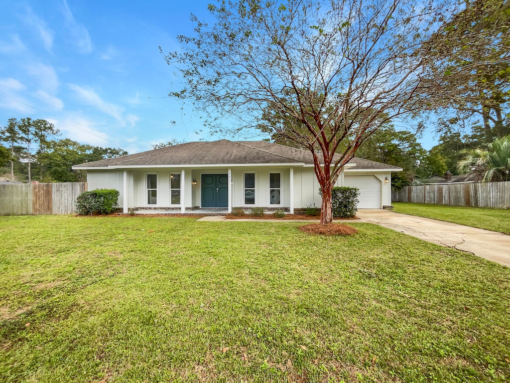 ranch-style house featuring a front lawn, covered porch, and a garage