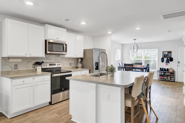 127 Rosefield Ct, Summerville, SC 29485 - kitchen with visible vents, a kitchen island with sink, light wood-style flooring, appliances with stainless steel finishes, and light countertops