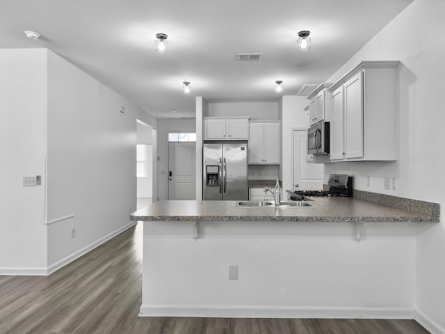 kitchen with appliances with stainless steel finishes, sink, white cabinets, and kitchen peninsula