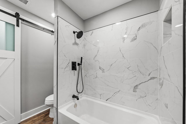 bathroom featuring hardwood / wood-style flooring, toilet, and tiled shower / bath