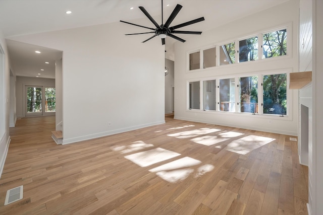 unfurnished living room featuring ceiling fan, light hardwood / wood-style flooring, high vaulted ceiling, and a healthy amount of sunlight