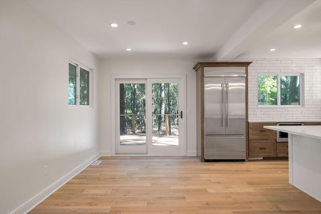 kitchen with light hardwood / wood-style flooring, stainless steel built in fridge, a wealth of natural light, and beverage cooler