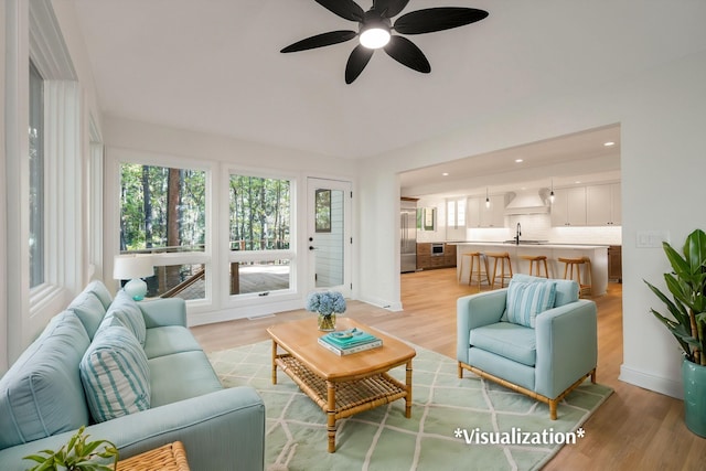 living room featuring ceiling fan, light wood-type flooring, and sink