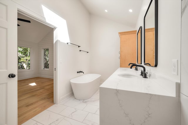 bathroom featuring a tub, hardwood / wood-style floors, vanity, and lofted ceiling