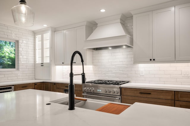 kitchen featuring decorative light fixtures, white cabinetry, and custom range hood