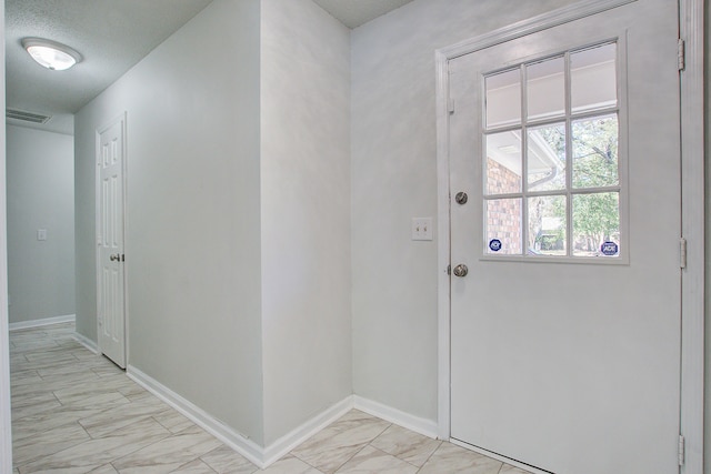 doorway to outside featuring a textured ceiling