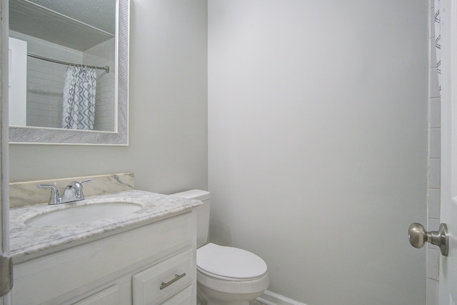 bathroom featuring a shower with curtain, vanity, toilet, and a textured ceiling