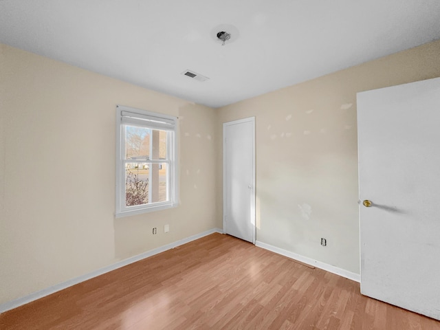 spare room featuring light wood-type flooring, baseboards, and visible vents