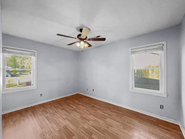 empty room featuring ceiling fan, baseboards, and wood finished floors