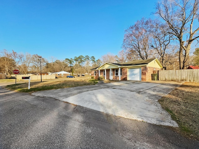 view of front facade featuring a garage, brick siding, fence, and driveway