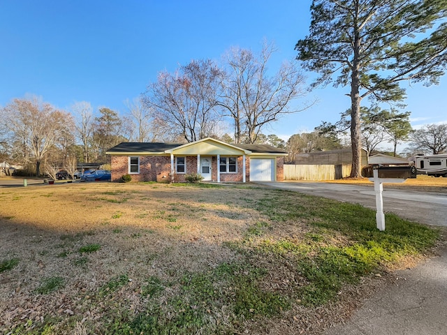 view of front of home featuring aphalt driveway, a garage, brick siding, fence, and a front yard