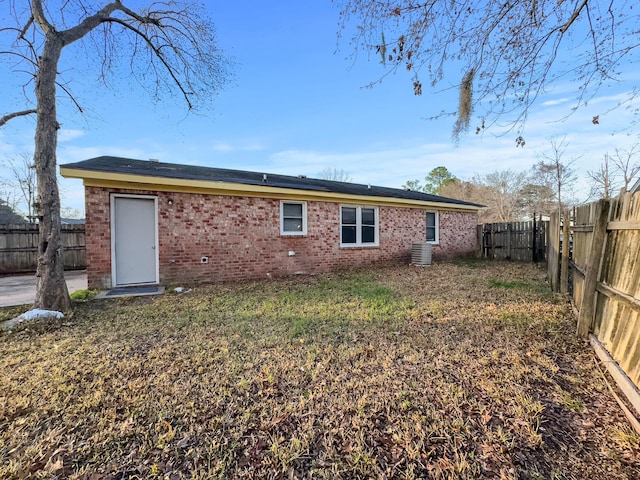 back of property with brick siding and a fenced backyard