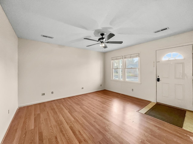 foyer entrance with a ceiling fan, visible vents, light wood-style flooring, and baseboards