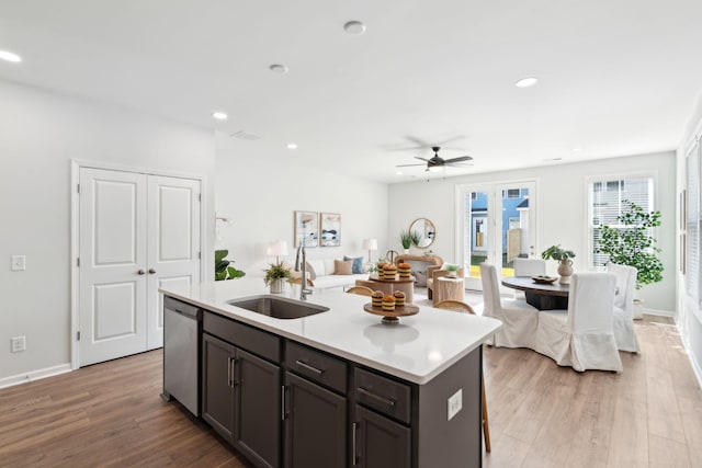 kitchen featuring sink, dishwasher, a kitchen island with sink, dark brown cabinets, and light hardwood / wood-style floors