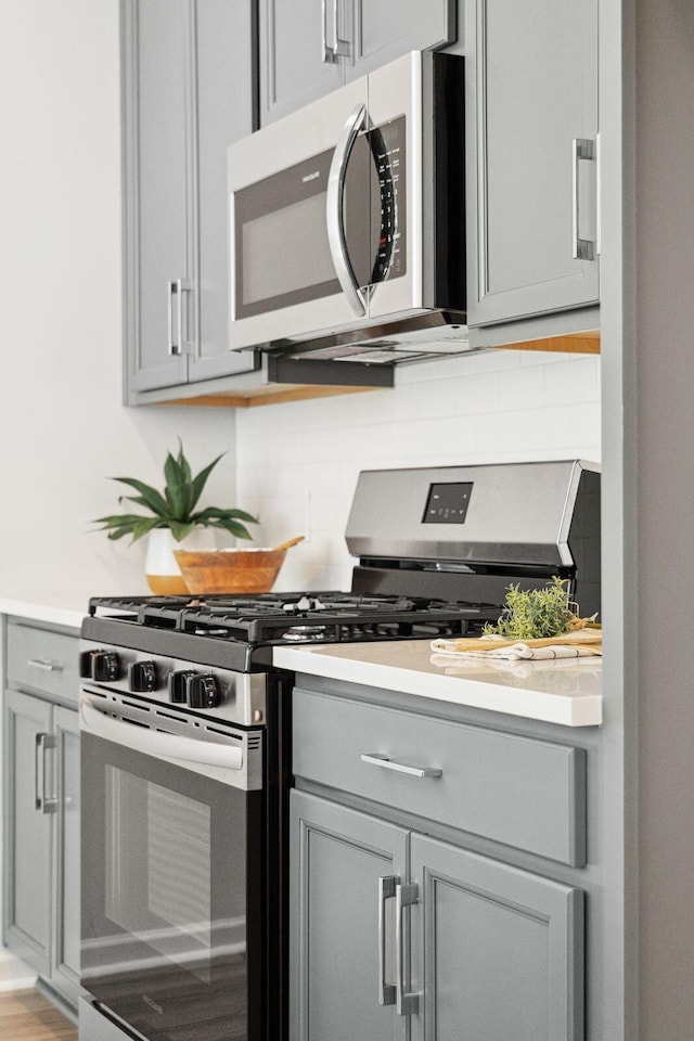 kitchen with decorative backsplash, gray cabinets, and appliances with stainless steel finishes