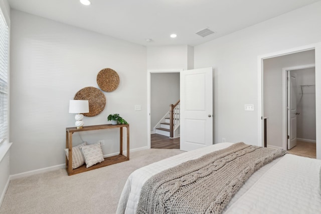 bedroom featuring a walk in closet and light colored carpet