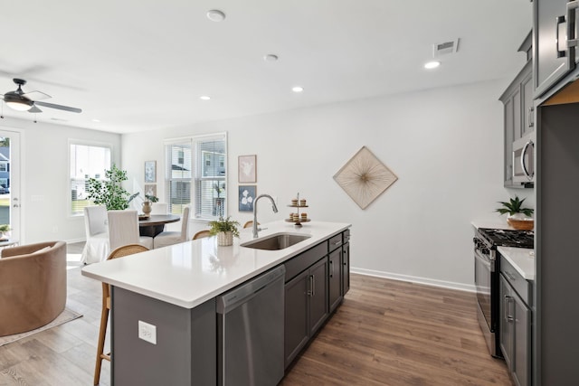 kitchen with a kitchen island with sink, sink, dark hardwood / wood-style floors, and appliances with stainless steel finishes