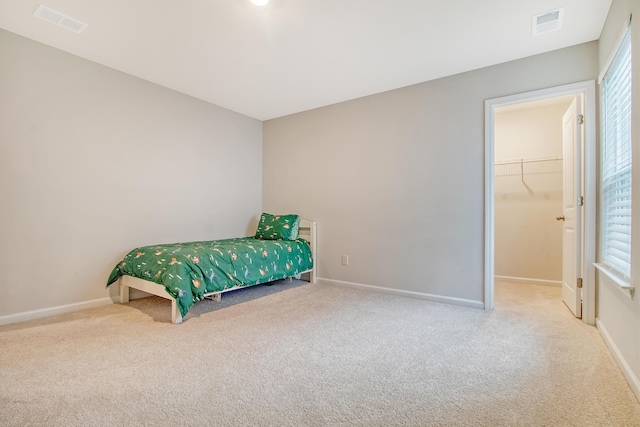 bedroom with a walk in closet, carpet floors, and a closet