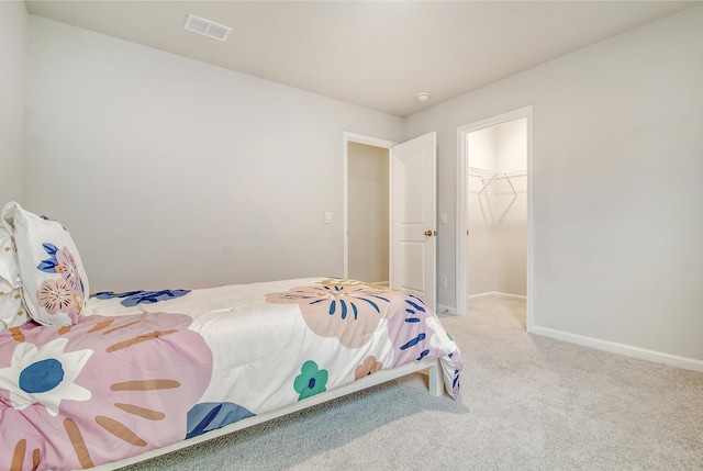 bedroom featuring light colored carpet, a spacious closet, and a closet