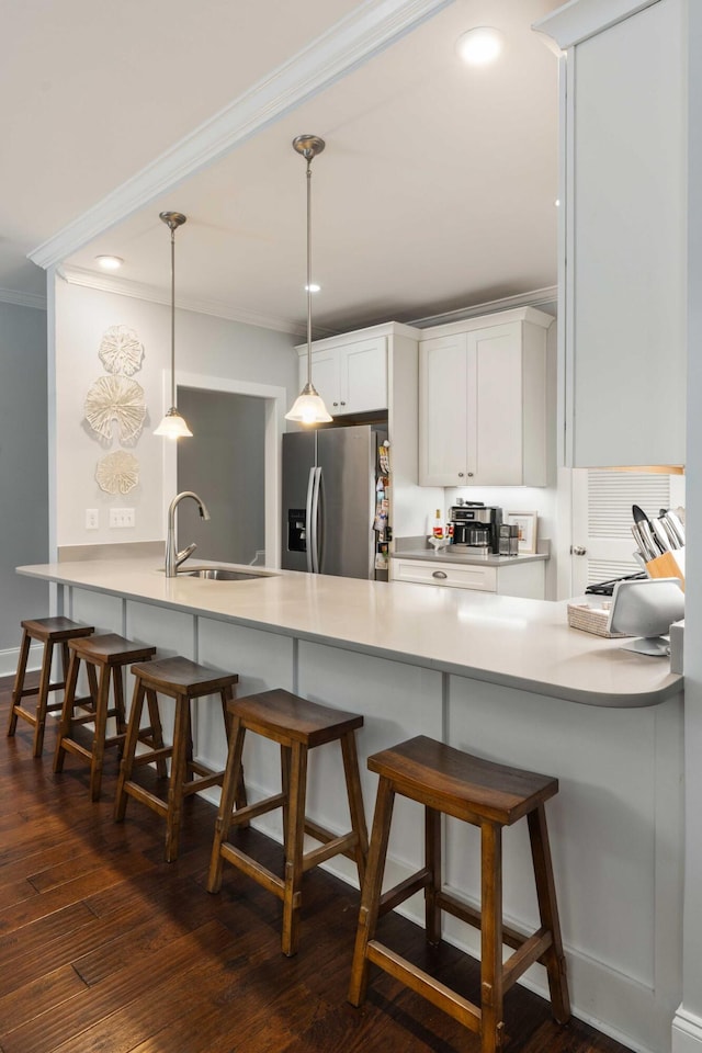 kitchen featuring a sink, stainless steel refrigerator with ice dispenser, a peninsula, crown molding, and white cabinetry