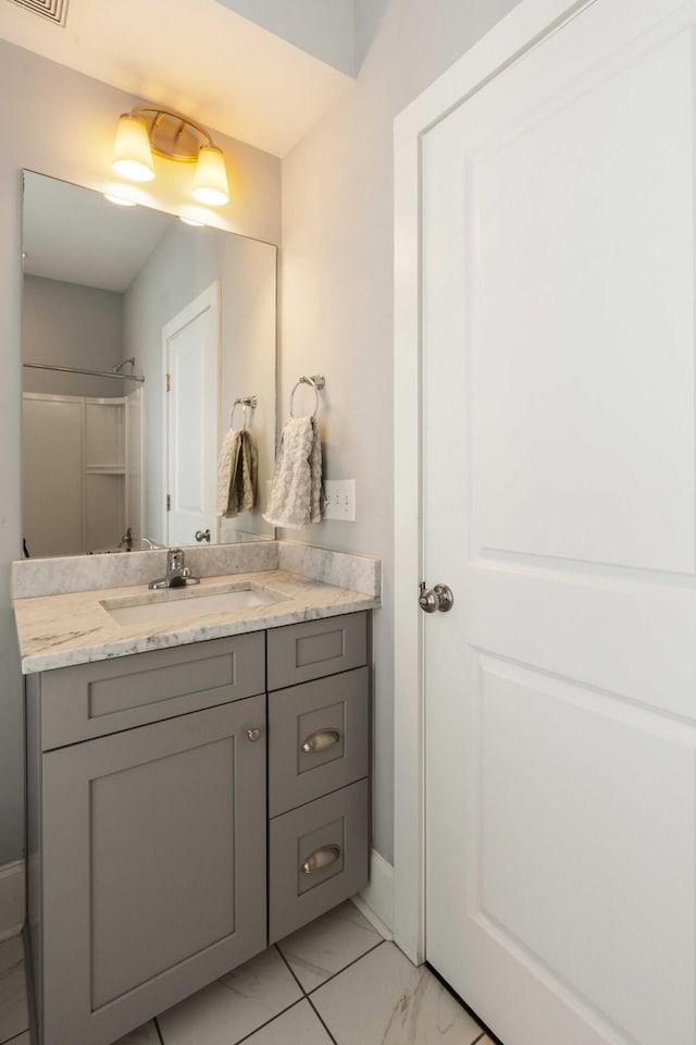 bathroom with vanity, baseboards, marble finish floors, and a shower