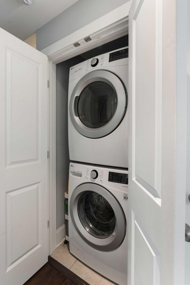 laundry area featuring estacked washer and dryer and dark wood-style flooring