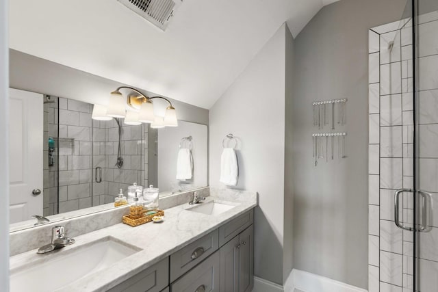 bathroom featuring a shower stall, vaulted ceiling, and double vanity